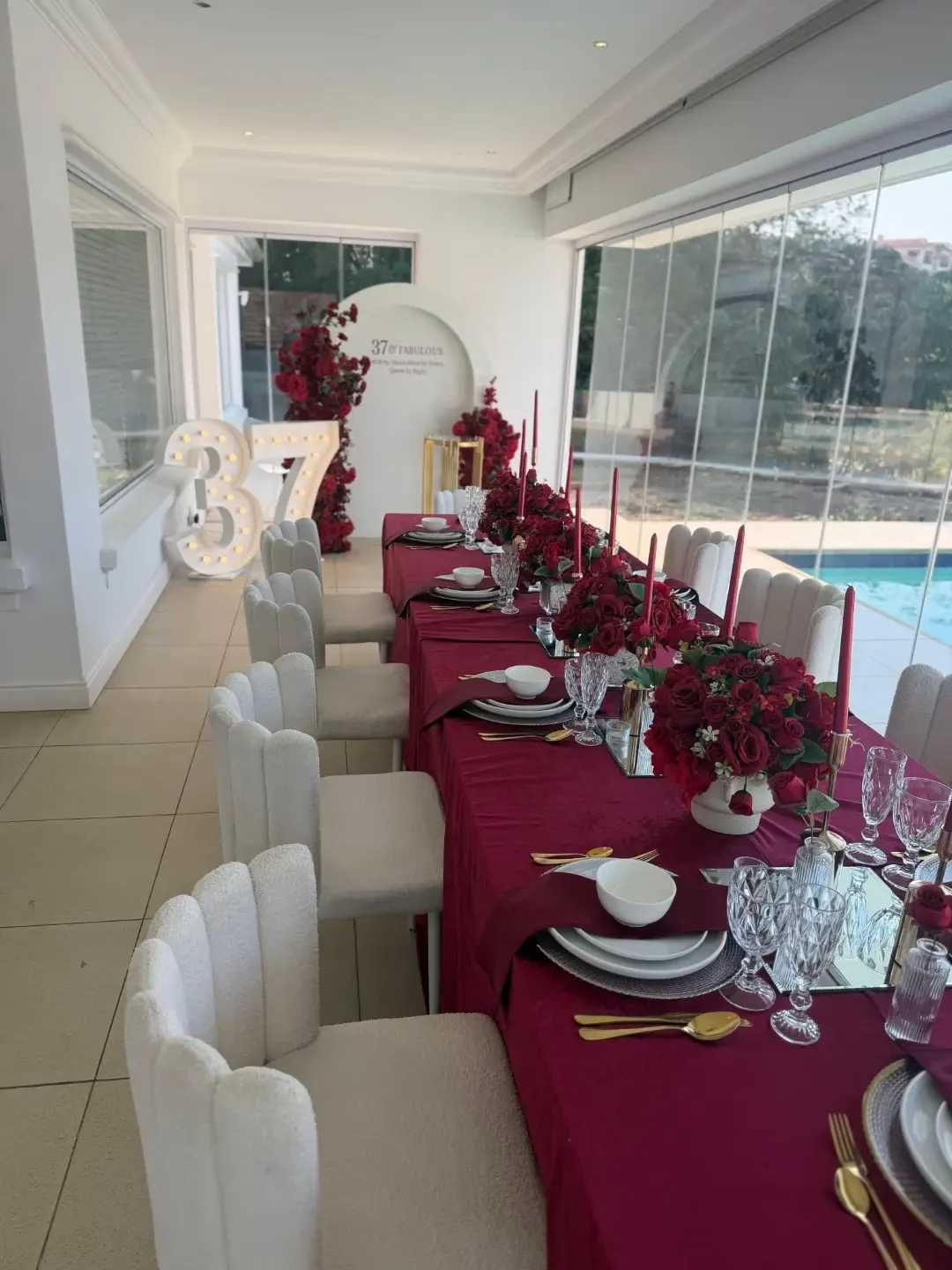 Deep burgundy long table with red roses and boucle chairs by Smartest Decor
