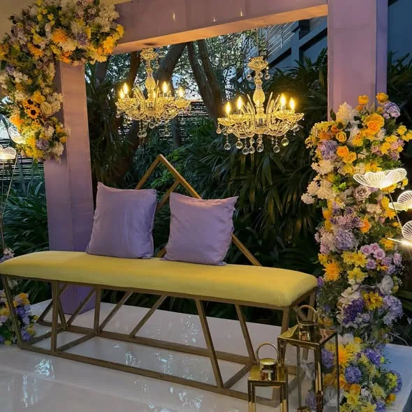 Gold and lilac florals around a sweetheart bench with chandeliers