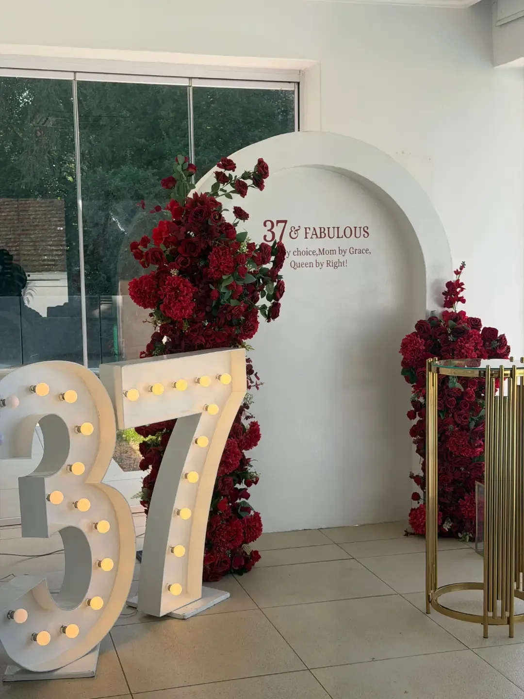 Deep red floral arch backdrop with marquee numbers by Smartest Decor